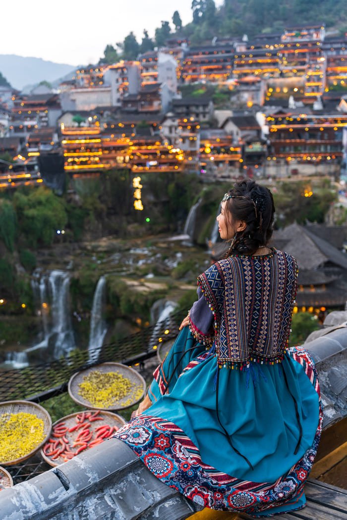 Mujer con traje tradicional viendo al horizonte una ciudad China