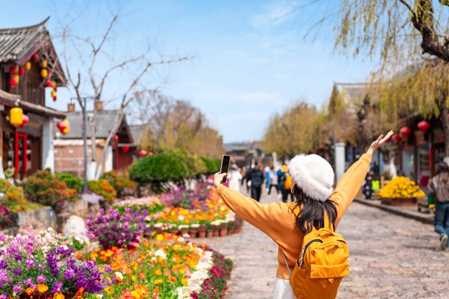 Mujer de brazos abiertos en los jardones de Lijiang